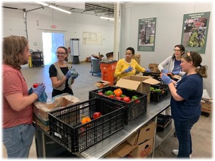 Volunteers stand at a table sorting fresh produce